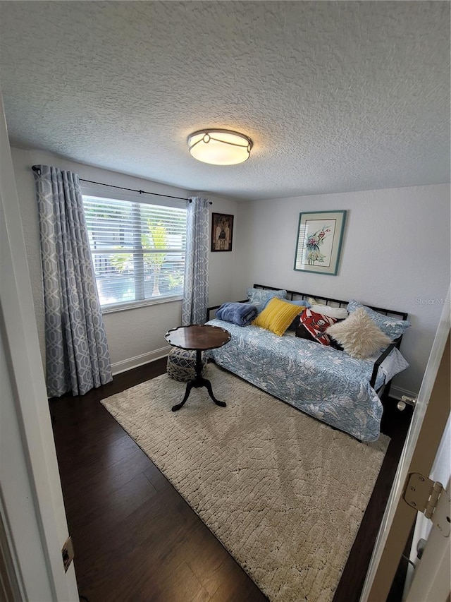 bedroom featuring wood finished floors, a textured ceiling, and baseboards