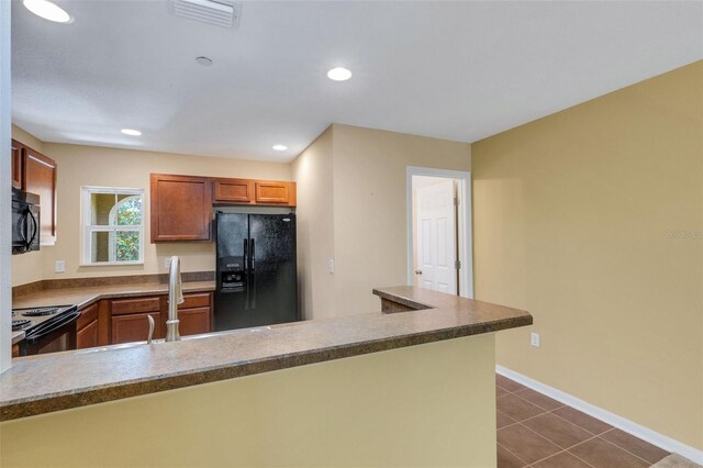 9013 White Sage Loop, Lakewood Ranch, FL 34202 - kitchen featuring black appliances, dark tile patterned floors, a peninsula, baseboards, and brown cabinets