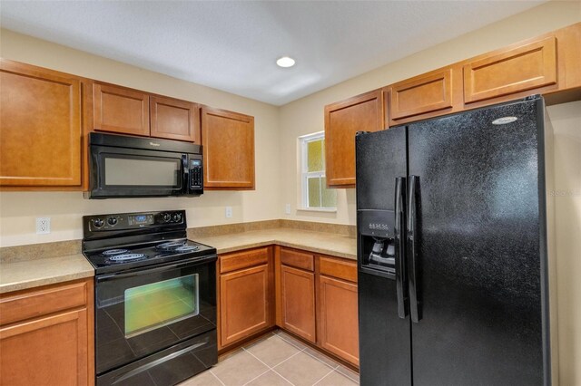 9013 White Sage Loop, Lakewood Ranch, FL 34202 - kitchen featuring black appliances, light countertops, light tile patterned floors, brown cabinets, and recessed lighting
