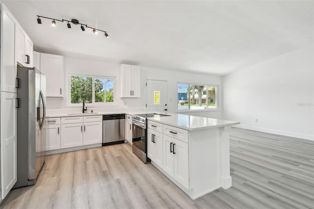 695 Sunset Dr, Tarpon Springs, FL 34689 - kitchen featuring appliances with stainless steel finishes, light wood-style floors, a peninsula, a sink, and light countertops