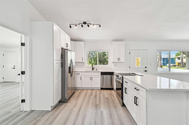 695 Sunset Dr, Tarpon Springs, FL 34689 - kitchen featuring stainless steel appliances, a sink, light wood-style floors, a peninsula, and light countertops