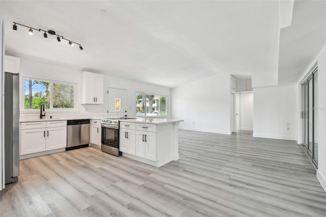 695 Sunset Dr, Tarpon Springs, FL 34689 - kitchen with stainless steel appliances, a peninsula, plenty of natural light, light wood-style floors, and vaulted ceiling