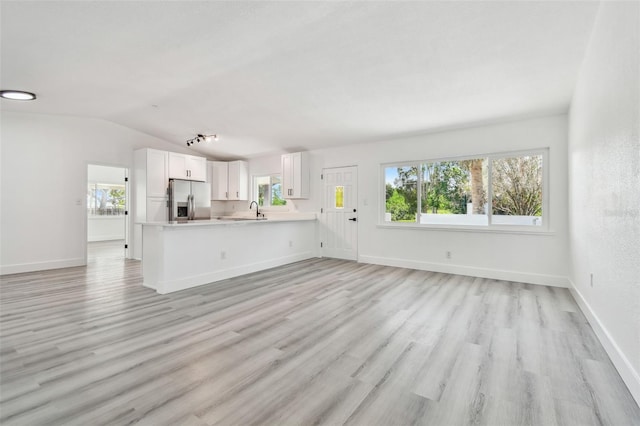 695 Sunset Dr, Tarpon Springs, FL 34689 - unfurnished living room with vaulted ceiling, light wood-style floors, and baseboards