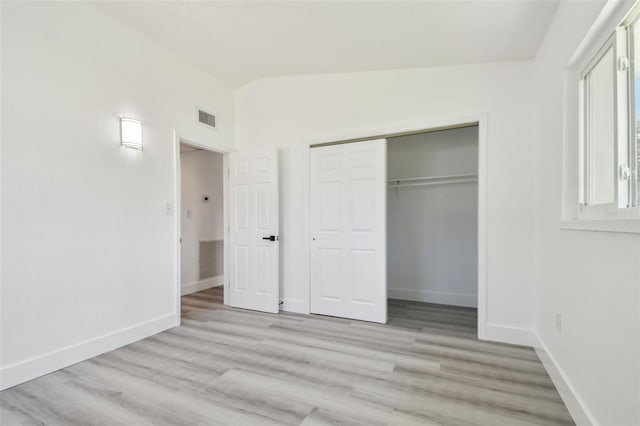 695 Sunset Dr, Tarpon Springs, FL 34689 - unfurnished bedroom featuring light wood finished floors, baseboards, a closet, and vaulted ceiling