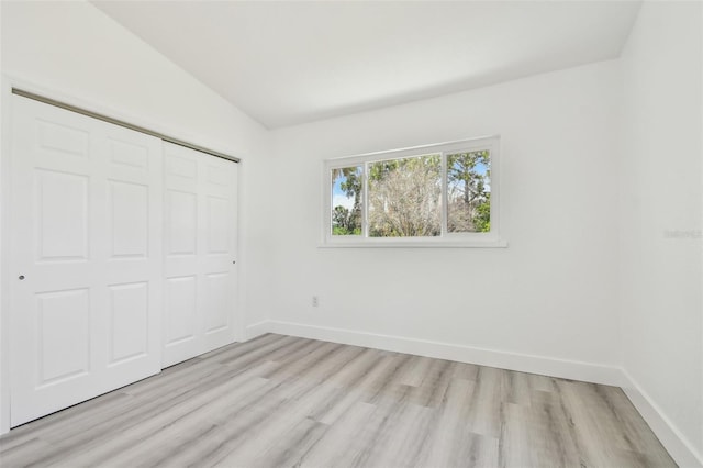 695 Sunset Dr, Tarpon Springs, FL 34689 - unfurnished bedroom featuring light wood-style floors, vaulted ceiling, a closet, and baseboards