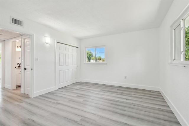 695 Sunset Dr, Tarpon Springs, FL 34689 - unfurnished bedroom with multiple windows, light wood-type flooring, baseboards, and a sink