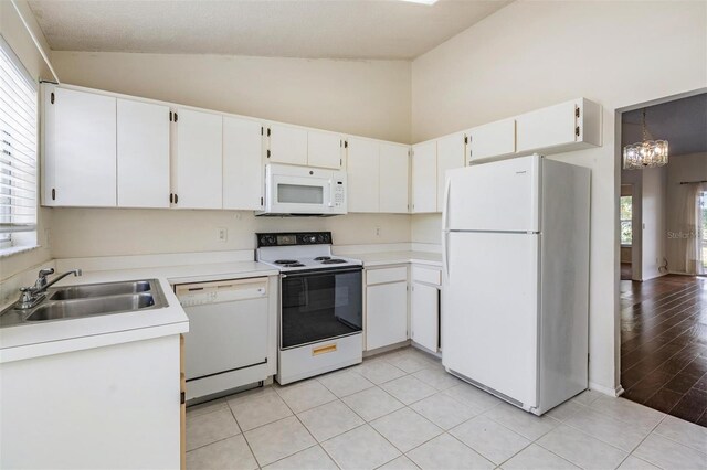 2355 Bentley Dr, Palm Harbor, FL 34684 - kitchen with white appliances, a sink, a chandelier, light countertops, and high vaulted ceiling