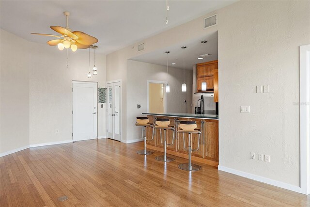 400 4th Ave S Unit 508, Saint Petersburg, FL 33701 - kitchen featuring ceiling fan, light wood-style floors, brown cabinets, a breakfast bar, and baseboards