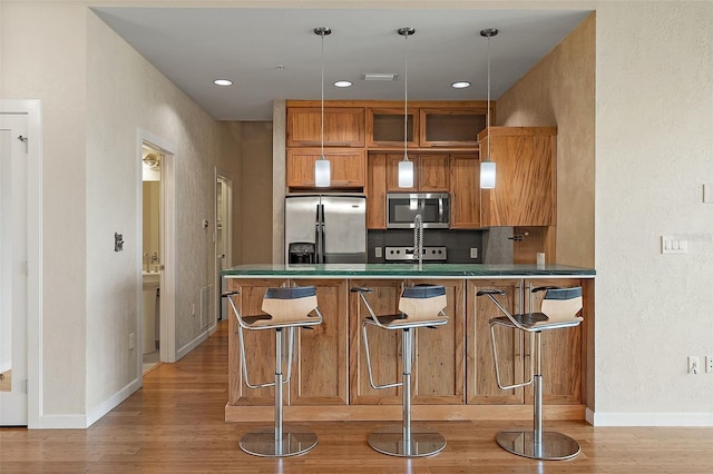 400 4th Ave S Unit 508, Saint Petersburg, FL 33701 - kitchen with appliances with stainless steel finishes, baseboards, light wood-type flooring, brown cabinetry, and a textured wall