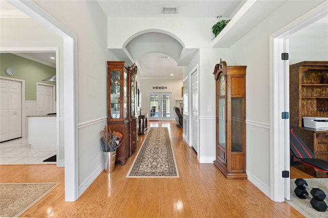 9830 Caribou Trl, Dade City, FL 33525 - corridor featuring light wood-style floors, arched walkways, french doors, ornamental molding, and baseboards