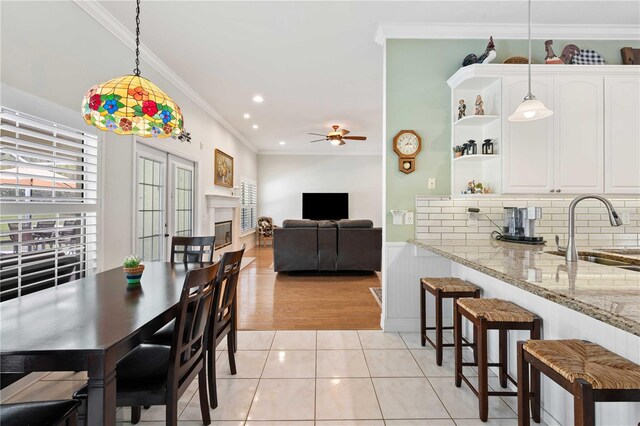 9830 Caribou Trl, Dade City, FL 33525 - dining area with plenty of natural light, crown molding, a ceiling fan, a glass covered fireplace, and light tile patterned floors
