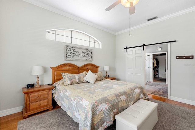 9830 Caribou Trl, Dade City, FL 33525 - bedroom with a barn door, crown molding, wood finished floors, baseboards, and a closet