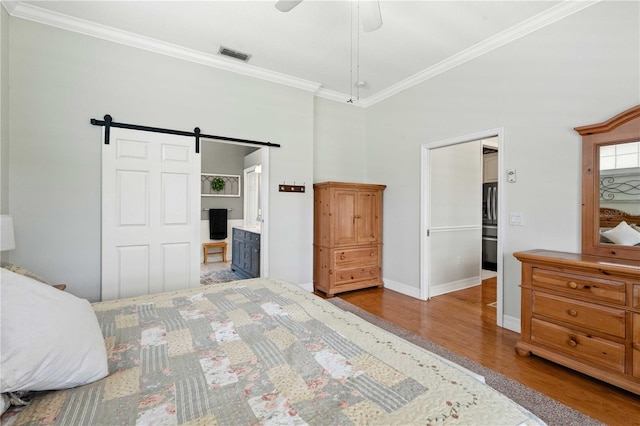 9830 Caribou Trl, Dade City, FL 33525 - bedroom featuring ornamental molding, wood finished floors, a barn door, baseboards, and a towering ceiling