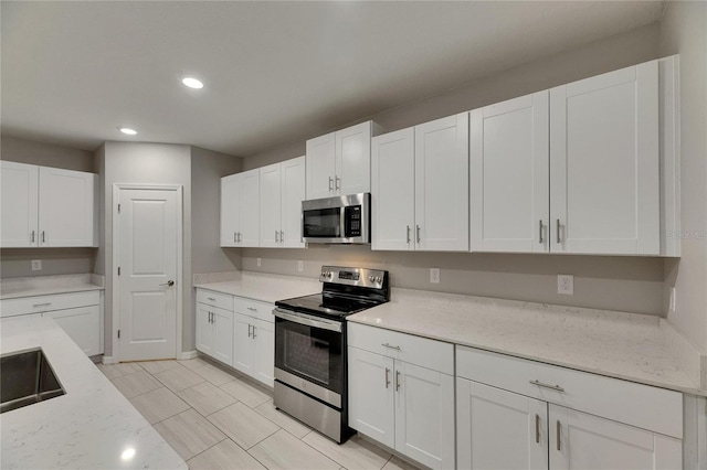 12617 Maple Bonsai Dr, Riverview, FL 33579 - kitchen with appliances with stainless steel finishes, recessed lighting, white cabinets, light stone counters, and light tile patterned floors