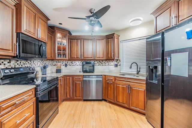 10954 96th St, Largo, FL 33773 - kitchen featuring black appliances, a sink, ceiling fan, light wood-type flooring, and brown cabinets