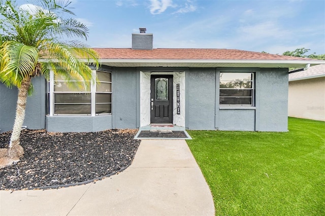 10954 96th St, Largo, FL 33773 - property entrance featuring stucco siding, a yard, and a chimney