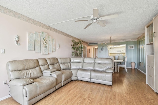 17920 Gulf Blvd Unit 208, Redington Shores, FL 33708 - living room featuring a textured ceiling, a ceiling fan, wood finished floors, baseboards, and a chandelier