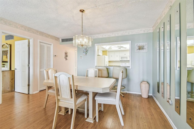 17920 Gulf Blvd Unit 208, Redington Shores, FL 33708 - dining area featuring a textured ceiling, a chandelier, light wood-type flooring, and baseboards