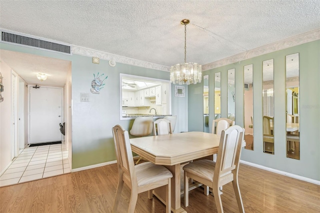 17920 Gulf Blvd Unit 208, Redington Shores, FL 33708 - dining space featuring a textured ceiling, wood finished floors, a chandelier, and baseboards