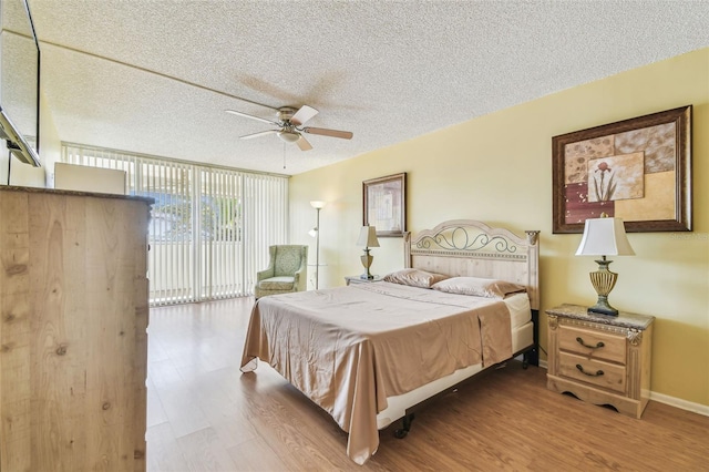 17920 Gulf Blvd Unit 208, Redington Shores, FL 33708 - bedroom with a textured ceiling, wood finished floors, access to outside, baseboards, and a wall of windows