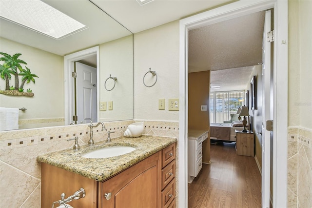 17920 Gulf Blvd Unit 208, Redington Shores, FL 33708 - ensuite bathroom with vanity, tile walls, wood finished floors, and a wainscoted wall
