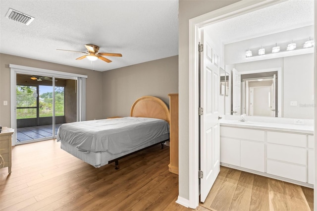 8175 Sturbridge Unit 8175, Weeki Wachee, FL 34613 - bedroom featuring access to exterior, light wood finished floors, a textured ceiling, ceiling fan, and ensuite bathroom
