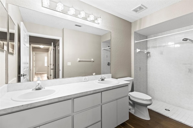 8175 Sturbridge Unit 8175, Weeki Wachee, FL 34613 - full bathroom featuring wood finished floors, double vanity, a tile shower, a textured ceiling, and a textured wall