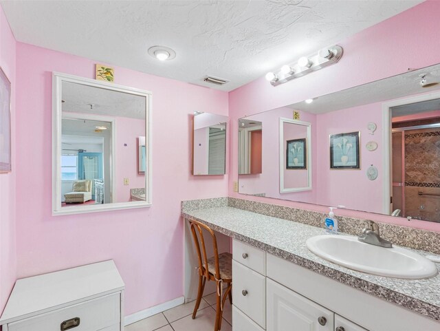 13500 Gulf Blvd Unit 706, Madeira Beach, FL 33708 - bathroom featuring vanity, a shower with shower door, a textured ceiling, tile patterned floors, and baseboards