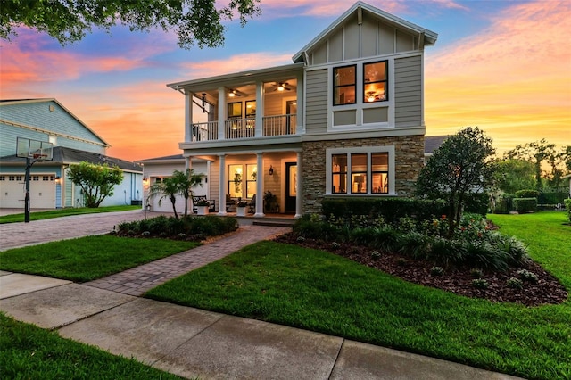 15936 Ternglade Dr, Lithia, FL 33547 - view of front facade featuring a balcony, stone siding, a porch, board and batten siding, and a front lawn