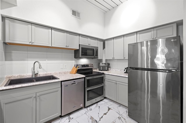 2410 W Azeele St Unit 214, Tampa, FL 33609 - kitchen featuring stainless steel appliances, gray cabinetry, light marble finish flooring, a towering ceiling, and light stone counters