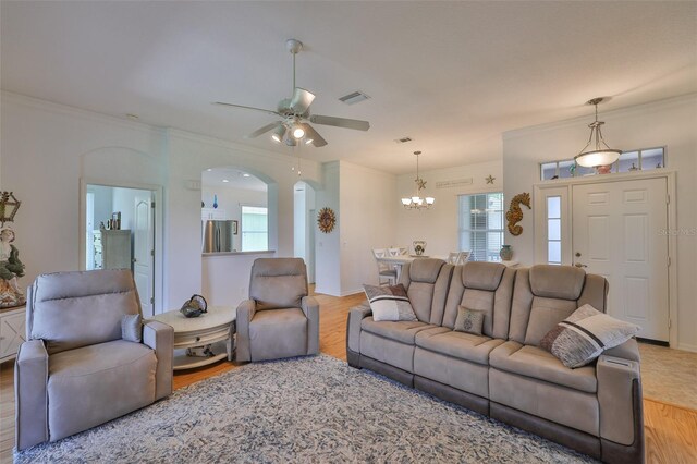 2316 Lyndhurst Dr, Sun City Center, FL 33573 - living area featuring wood finished floors, arched walkways, a chandelier, a ceiling fan, and ornamental molding