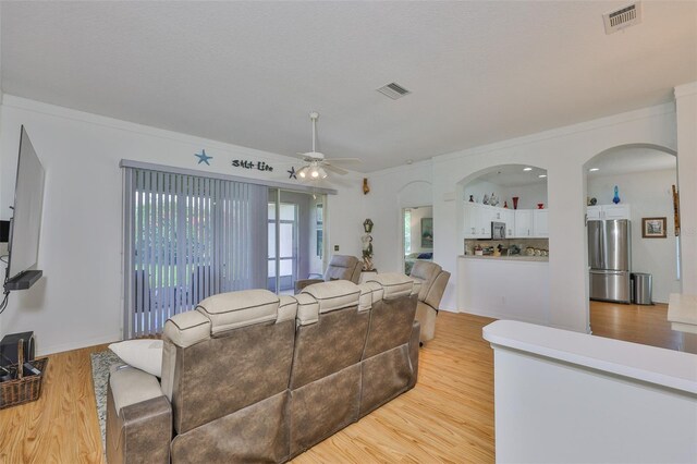 2316 Lyndhurst Dr, Sun City Center, FL 33573 - living room featuring ceiling fan, light wood-style flooring, arched walkways, and ornamental molding