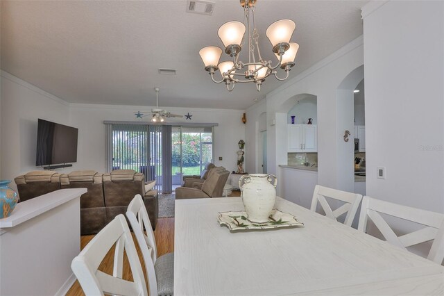 2316 Lyndhurst Dr, Sun City Center, FL 33573 - dining room featuring ceiling fan, wood finished floors, arched walkways, a chandelier, and crown molding