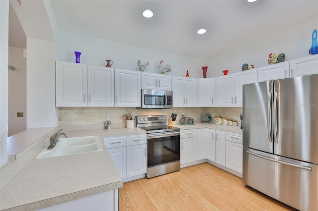 2316 Lyndhurst Dr, Sun City Center, FL 33573 - kitchen with appliances with stainless steel finishes, a sink, light wood finished floors, light countertops, and tasteful backsplash
