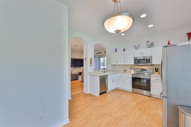 2316 Lyndhurst Dr, Sun City Center, FL 33573 - kitchen featuring appliances with stainless steel finishes, a sink, arched walkways, light wood-type flooring, and light countertops