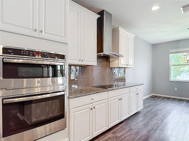 7628 Surf Reed Way, Wesley Chapel, FL 33545 - kitchen featuring stainless steel double oven, wall chimney exhaust hood, baseboards, black electric cooktop, and dark wood finished floors