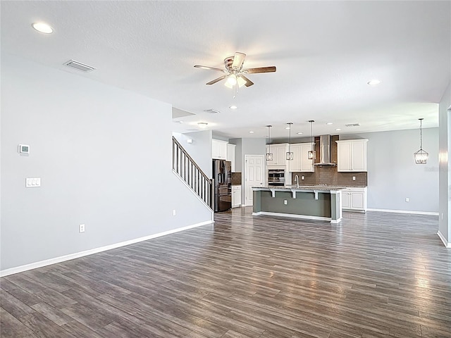 7628 Surf Reed Way, Wesley Chapel, FL 33545 - unfurnished living room with ceiling fan, dark wood-style flooring, stairs, baseboards, and recessed lighting