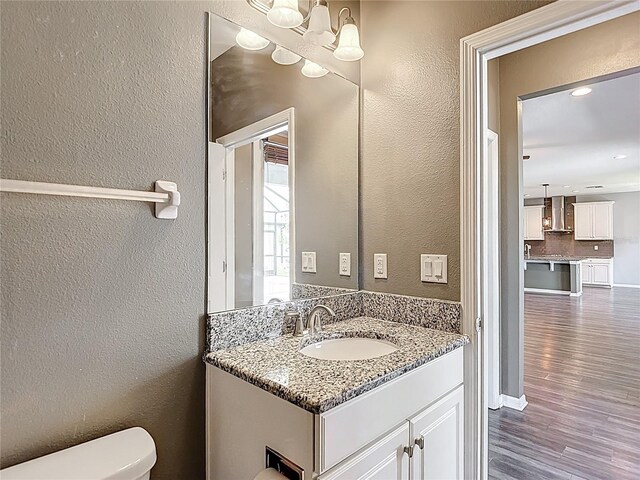 7628 Surf Reed Way, Wesley Chapel, FL 33545 - bathroom with vanity, toilet, a textured wall, wood finished floors, and a chandelier