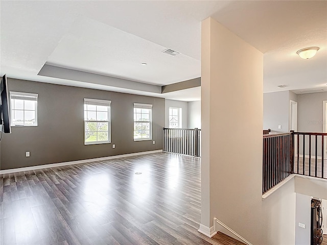 7628 Surf Reed Way, Wesley Chapel, FL 33545 - unfurnished room with wood finished floors, healthy amount of natural light, baseboards, and a tray ceiling