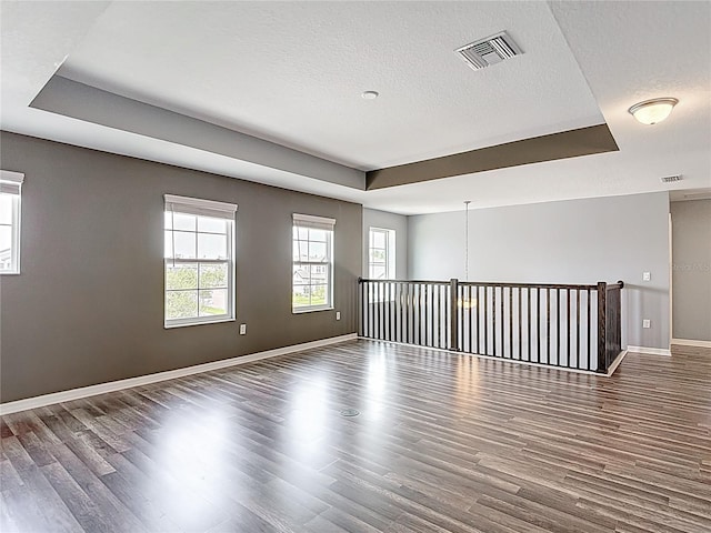 7628 Surf Reed Way, Wesley Chapel, FL 33545 - spare room featuring a tray ceiling, wood finished floors, baseboards, and a textured ceiling