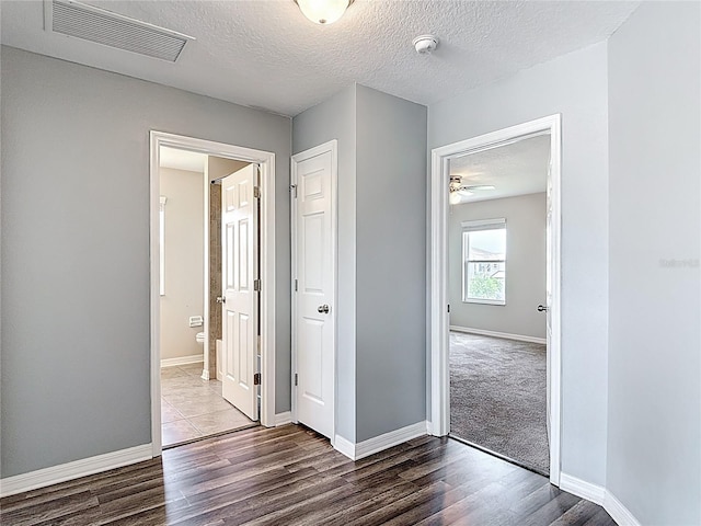 7628 Surf Reed Way, Wesley Chapel, FL 33545 - unfurnished bedroom featuring wood finished floors, a textured ceiling, baseboards, and ensuite bathroom