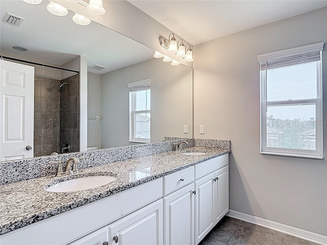 7628 Surf Reed Way, Wesley Chapel, FL 33545 - bathroom featuring double vanity, a tile shower, baseboards, and toilet