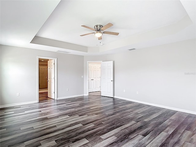 7628 Surf Reed Way, Wesley Chapel, FL 33545 - unfurnished bedroom with a tray ceiling, dark wood finished floors, and baseboards