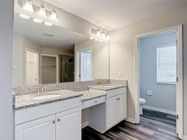 7628 Surf Reed Way, Wesley Chapel, FL 33545 - full bathroom featuring double vanity, wood finished floors, a spacious closet, a shower stall, and baseboards
