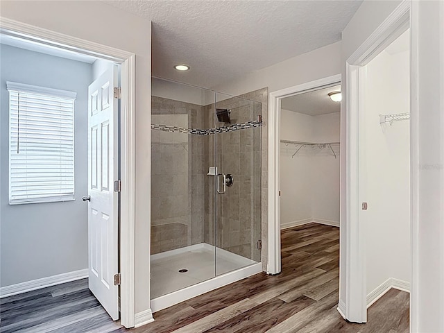 7628 Surf Reed Way, Wesley Chapel, FL 33545 - full bath with a stall shower, a walk in closet, wood finished floors, a textured ceiling, and baseboards