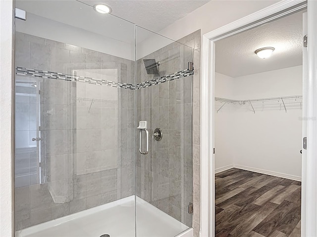7628 Surf Reed Way, Wesley Chapel, FL 33545 - full bath featuring a stall shower, a textured ceiling, a walk in closet, wood finished floors, and baseboards