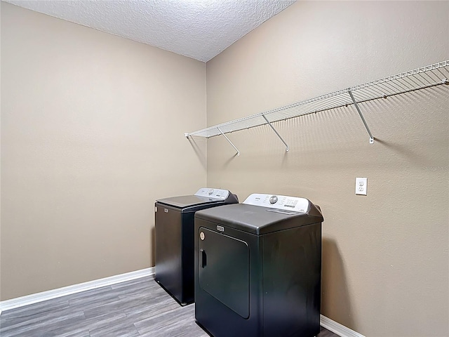 7628 Surf Reed Way, Wesley Chapel, FL 33545 - laundry area featuring washing machine and clothes dryer, light wood finished floors, baseboards, and a textured ceiling