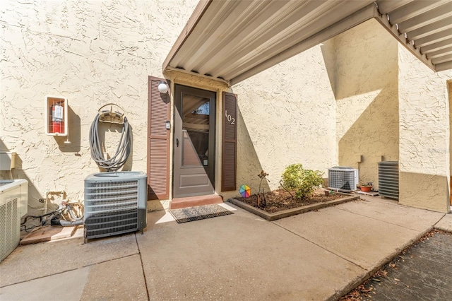 501 E Bay Dr Unit 102, Largo, FL 33770 - view of exterior entry featuring stucco siding, cooling unit, and a patio