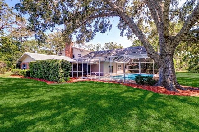 1670 Fox Rd, Clearwater, FL 33764 - rear view of house featuring a chimney, a lawn, an outdoor pool, and glass enclosure