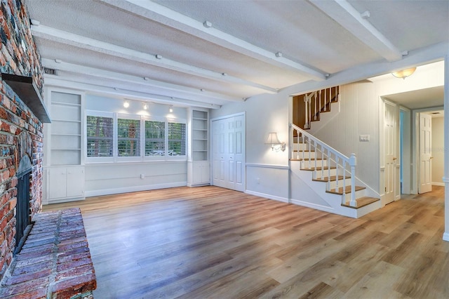 1670 Fox Rd, Clearwater, FL 33764 - unfurnished living room featuring a fireplace, stairway, wood finished floors, beam ceiling, and baseboards